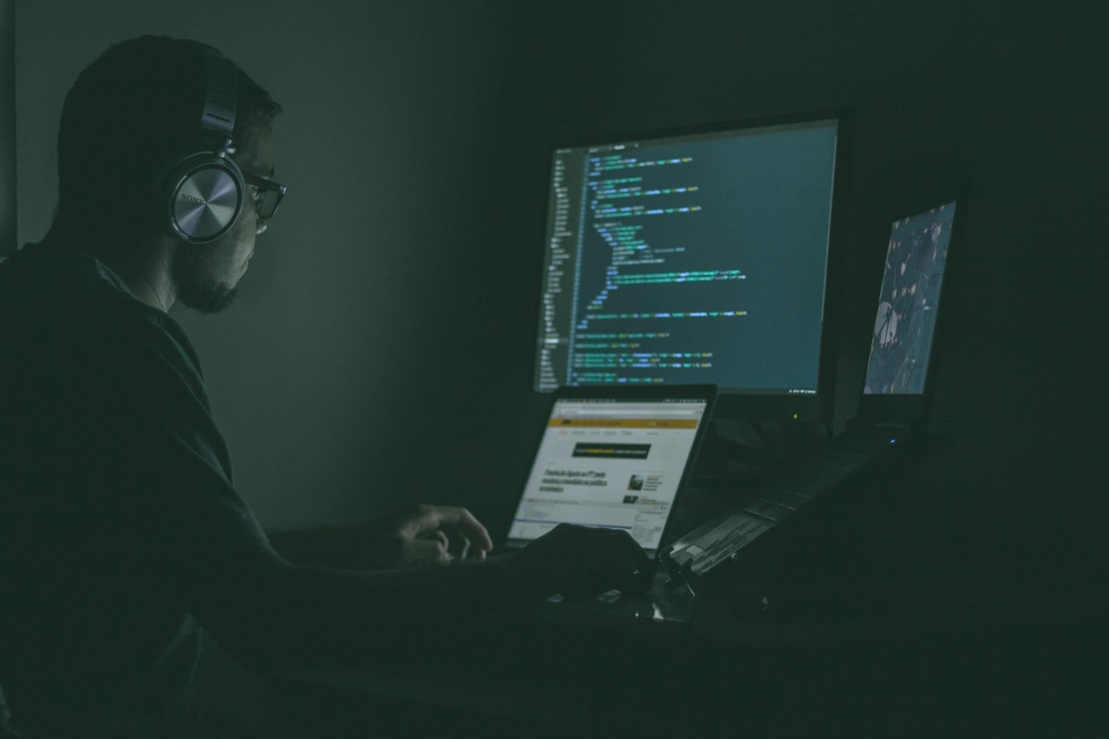 A person working on a laptop at night, illustrating phishing and online account-takeover risk.